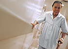 A senior woman walks holding a hand rail